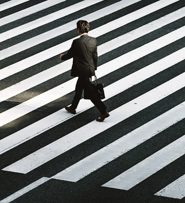 Man in a suit carrying a bag crosses a crosswalk
